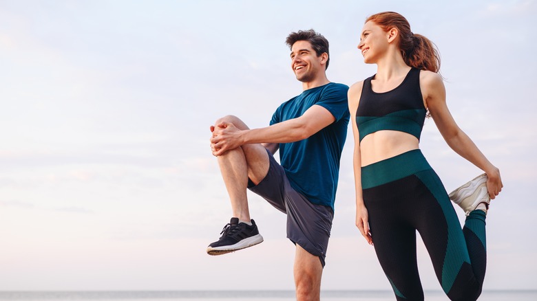 couple stretching before a run on the beach