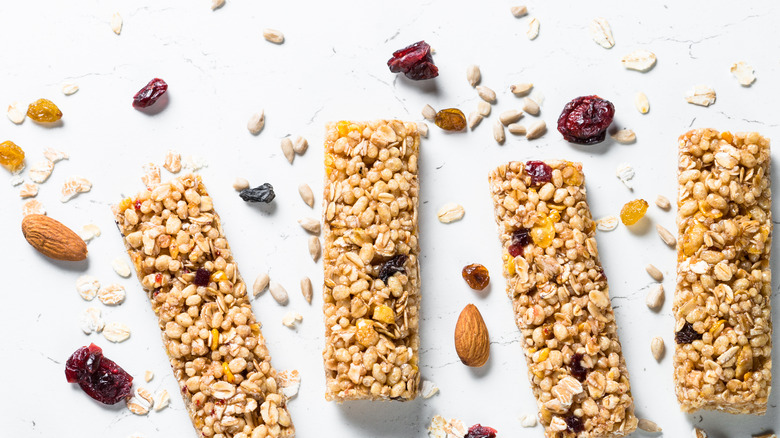 four granola bars on a white background with seeds and dried fruit around them