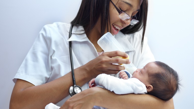 Doctor smiling and feeding baby