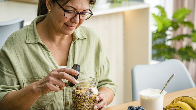 Woman opening jar of oats and nuts