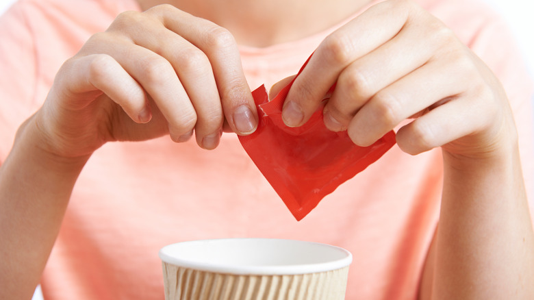 Woman adding artificial sweetener to coffee