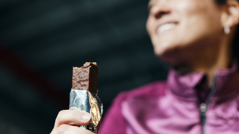 Smiling woman eating protein bar