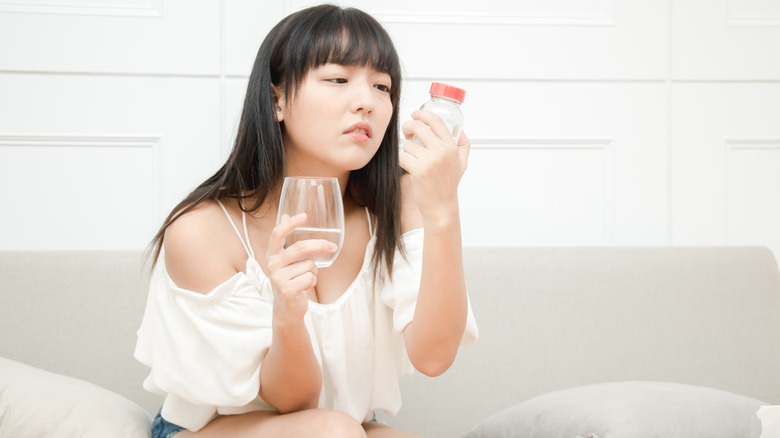 Woman holding painkillers and water