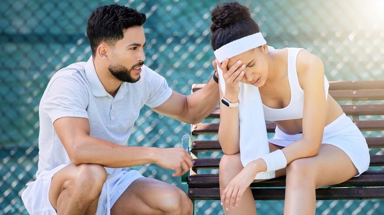 Exhausted tennis player sitting on bench