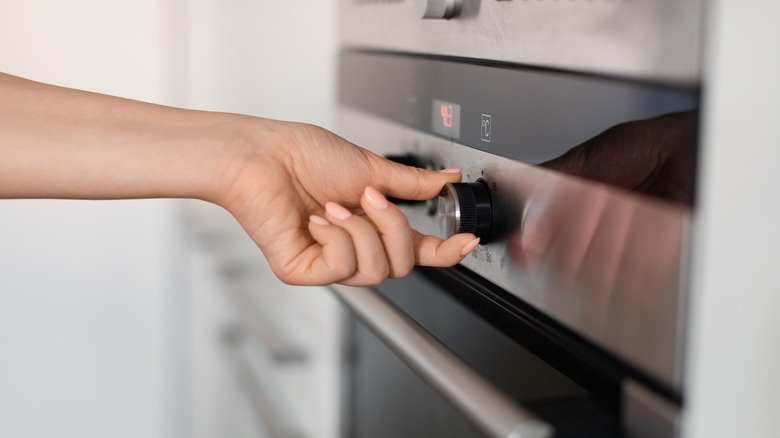 woman's hand turning knob on gas stove