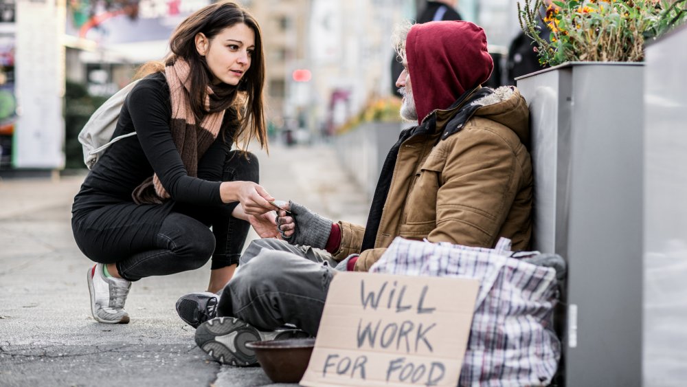 Woman giving money to homeless man