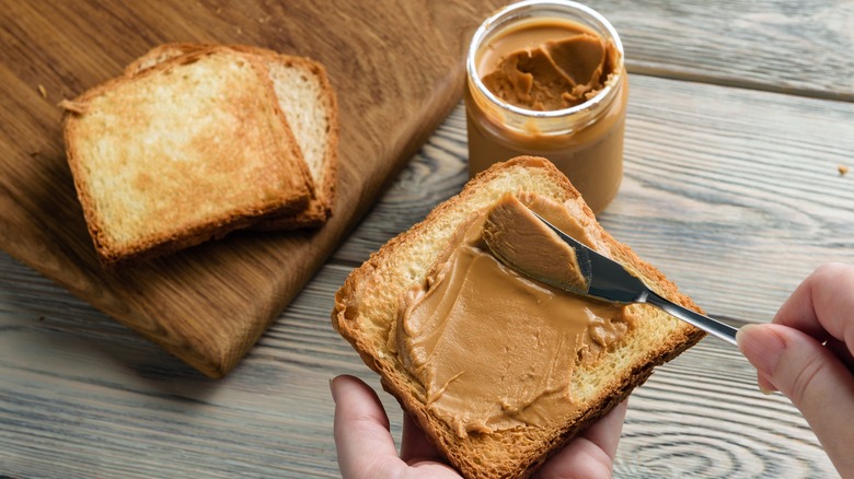 Spreading peanut butter on toast