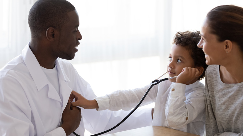 Child using stethoscope to listen to doctor's heart