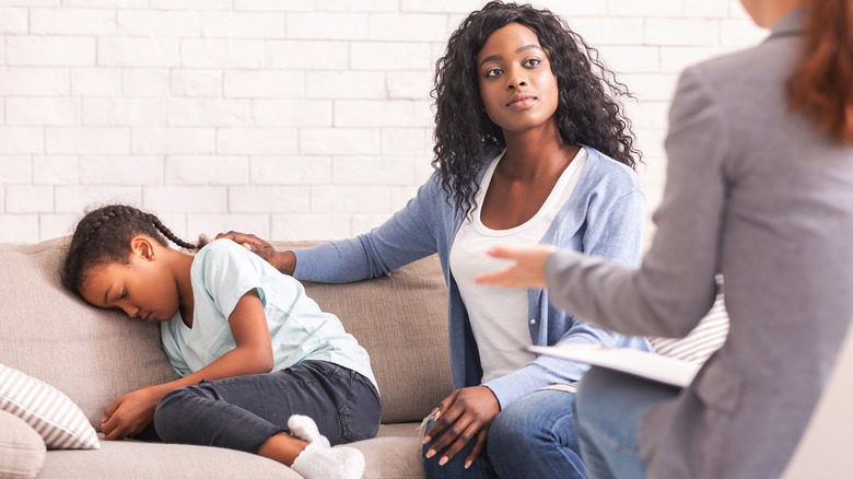 Sad child and mom speaking to doctor