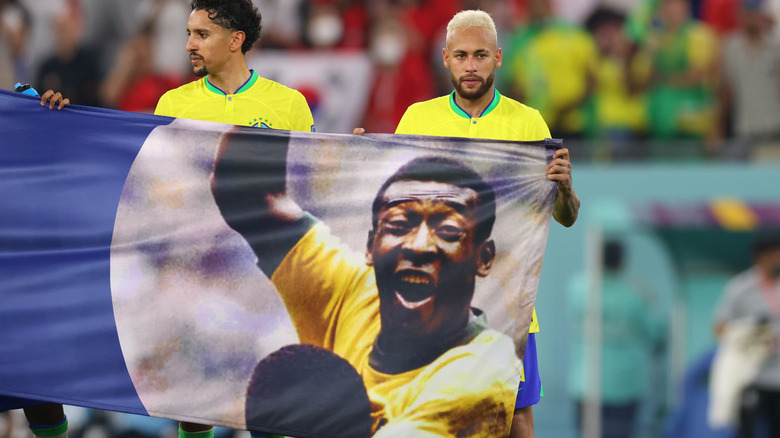 Brazilian soccer players hold a flag of Pelé