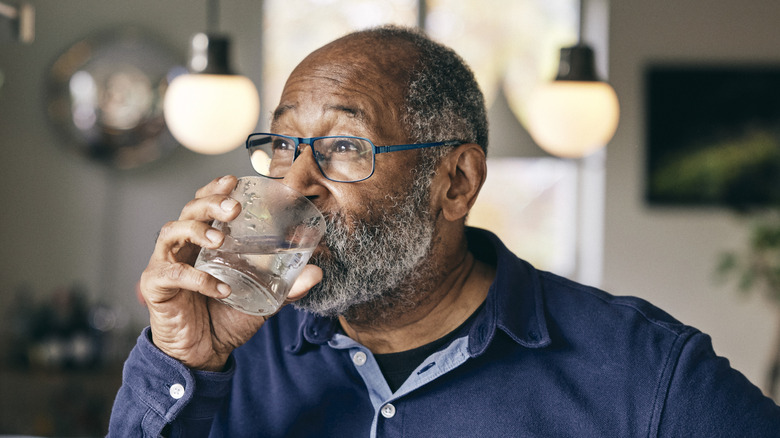 bearded bespectacled man drinking water