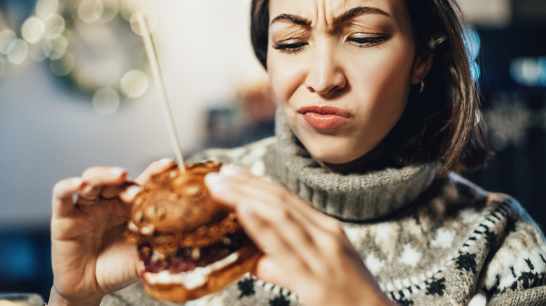a woman frowns at a burger