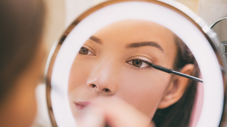 Woman applying mascara in mirror