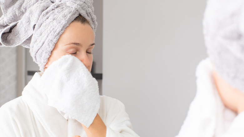 Woman wiping face with wash cloth