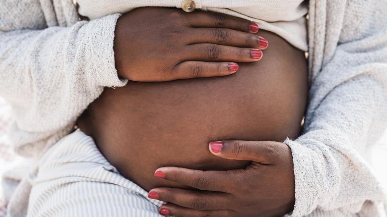 pregnant woman's hands cradling her belly 