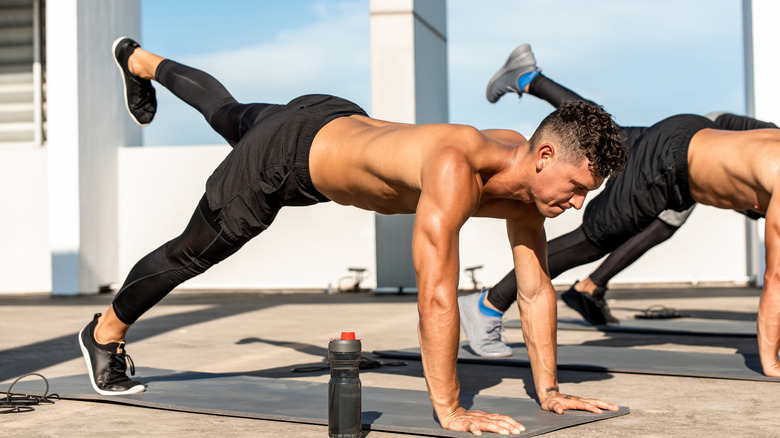 men doing plank leg raise