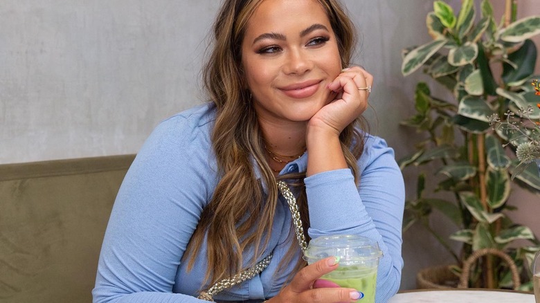 Catie Li sitting at a table holding a green drink