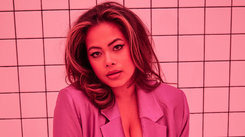 Catie Li sitting on a bench in a pink blazer