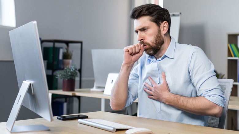 Man coughing at desk