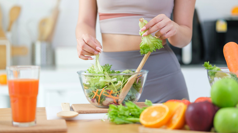 Woman in workout clothes preparing a salad promoting healthy habits