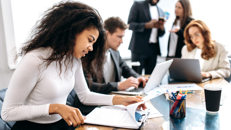 Woman at desk looking at paper on clipboard