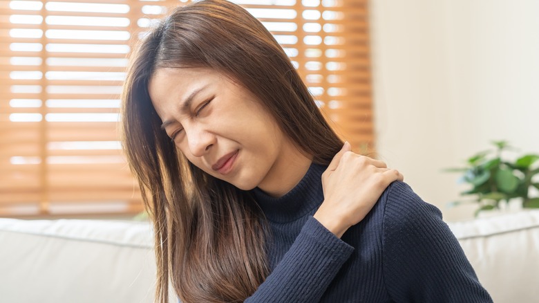 Woman in pain holding shoulder