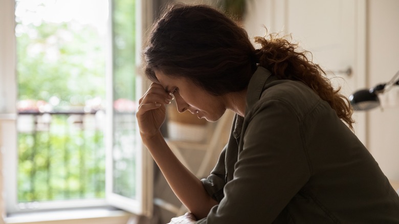 Woman with head in hand in anguish