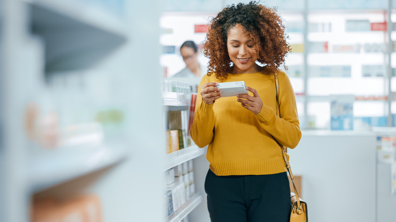 Smiling woman reading label on drugs