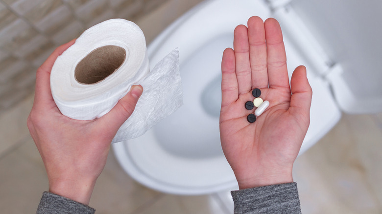 Person holding laxatives and toilet paper