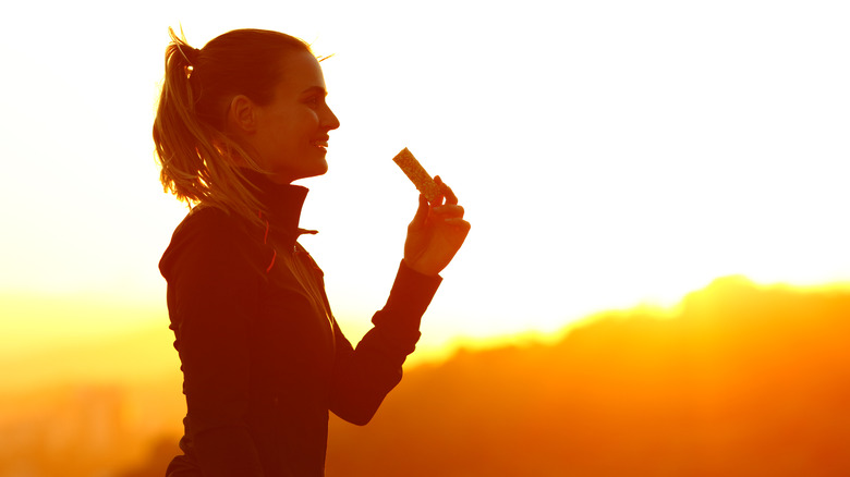 Woman eating a protein bar in the mountains at sunrise