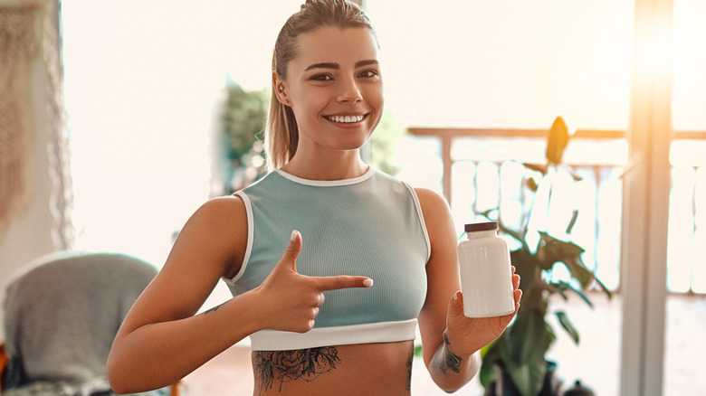 young woman holding protein shake bottle