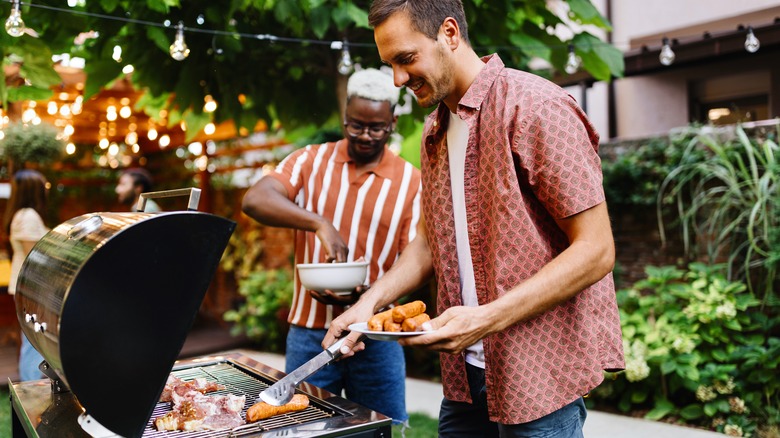 two men barbecuing red meat outside