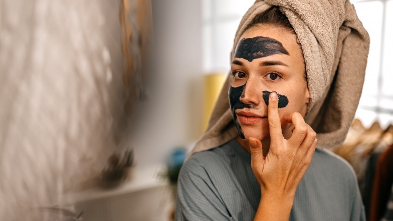 Woman applying face mask at home