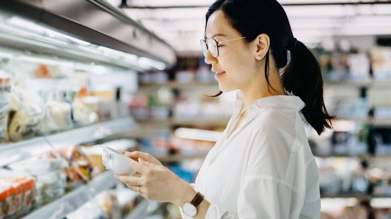 woman looking confidently at food label in grocery