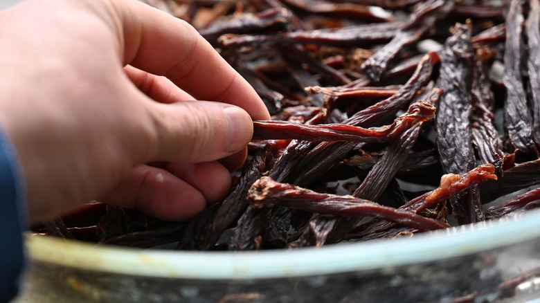 man's hand reaching for dried beef jerky