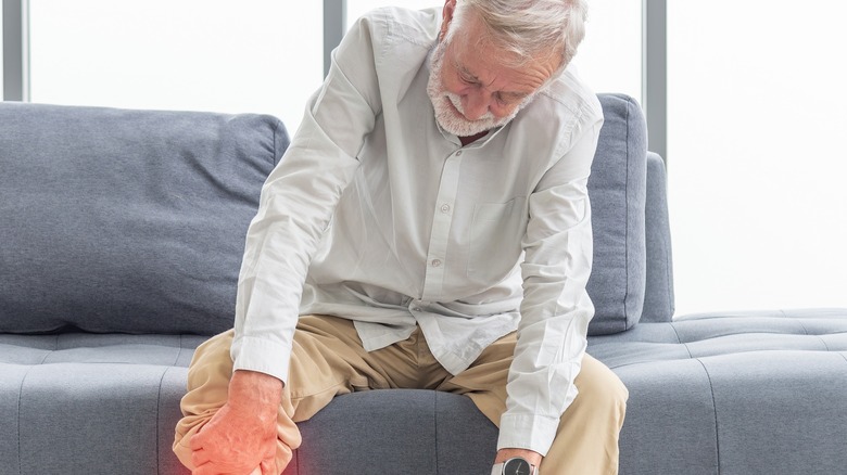 elderly man leaning over on couch