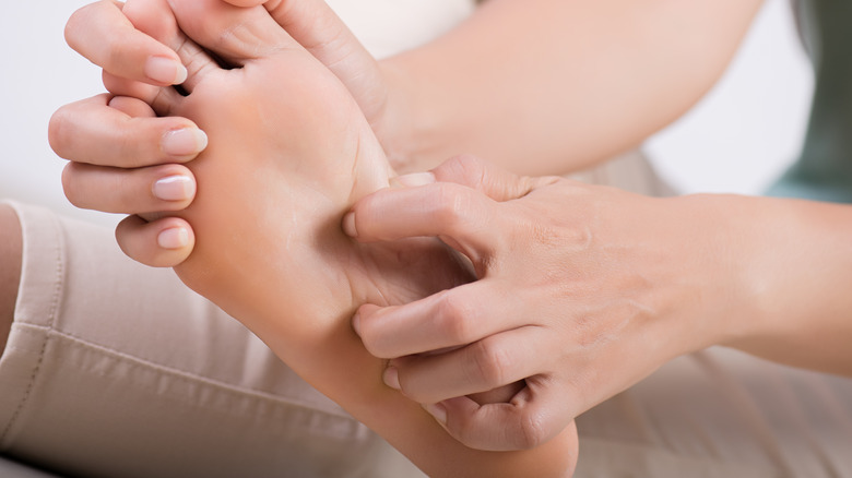 Woman scratching bottom of itching foot