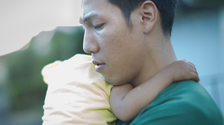 man with postpartum depression holding baby