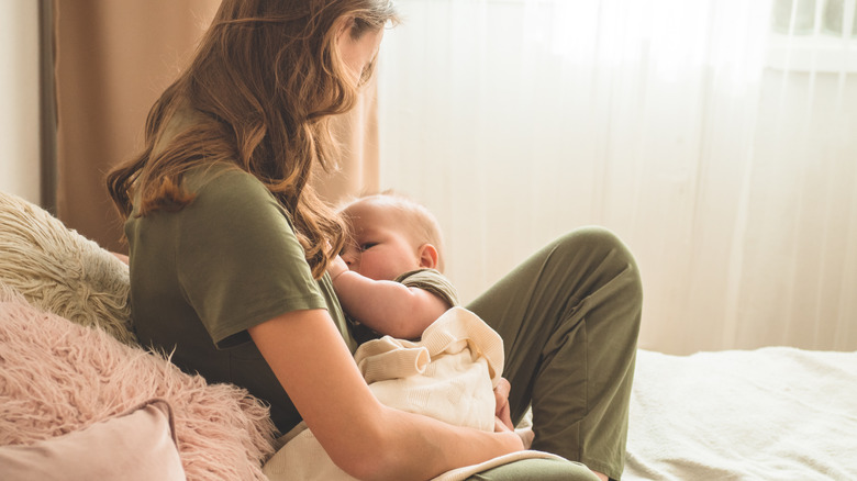 mother breastfeeding baby on bed