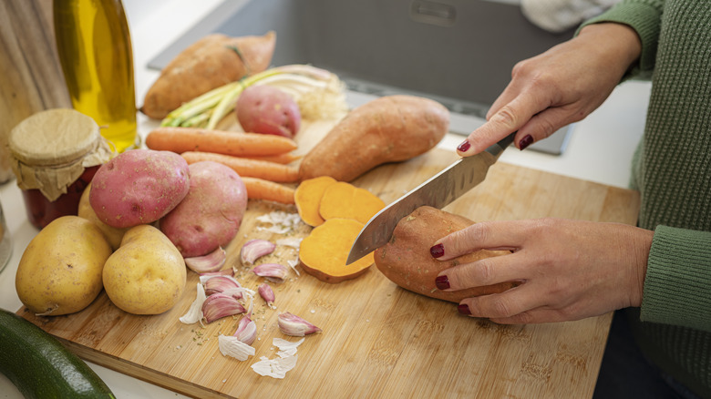 Hands using knife to slice potatoes