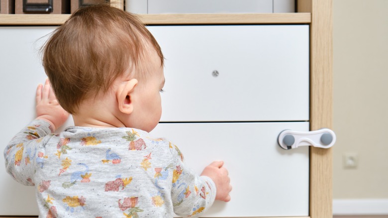 Child touching cabinet with child-resistant lock
