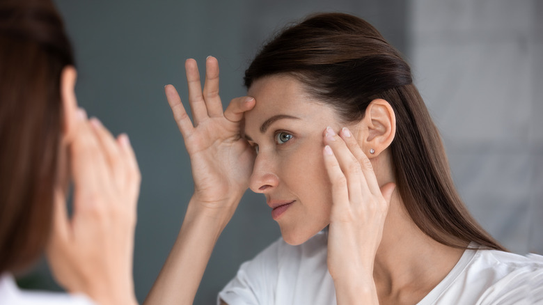 woman inspecting skin in mirror