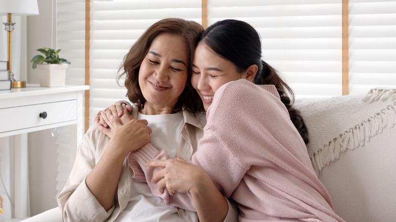 Two women hugging on couch