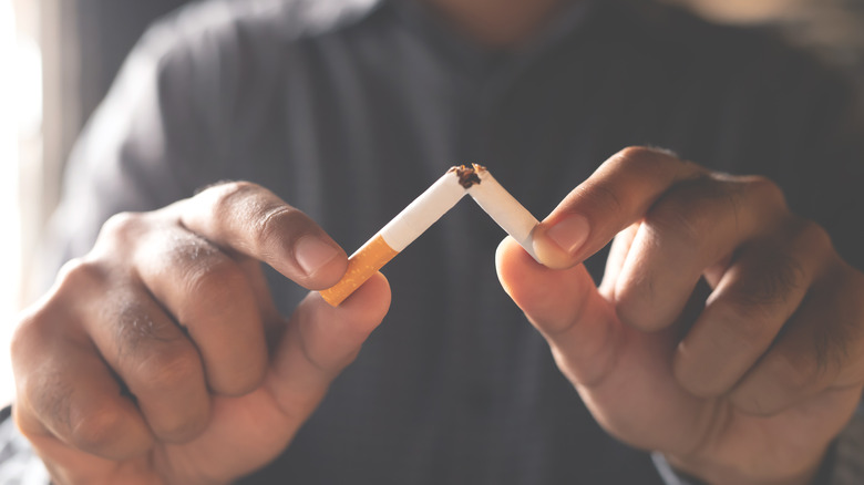 man bending cigarette in half