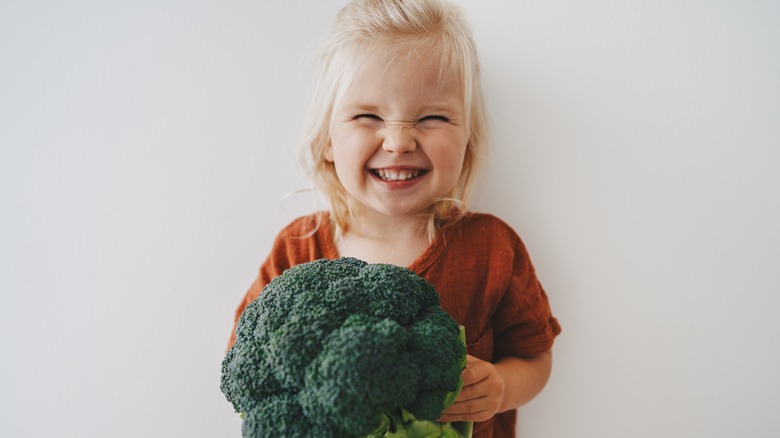 little girl holding broccoli