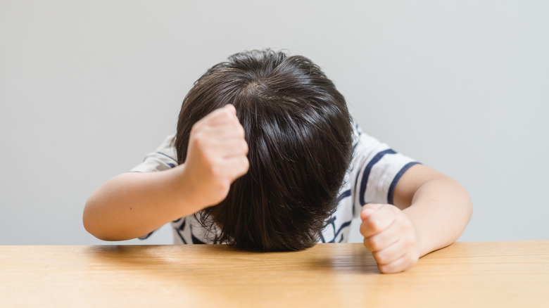 child banging fists on table