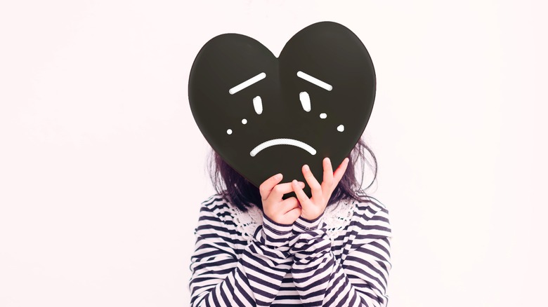 sad cutout of heart over a teenage face