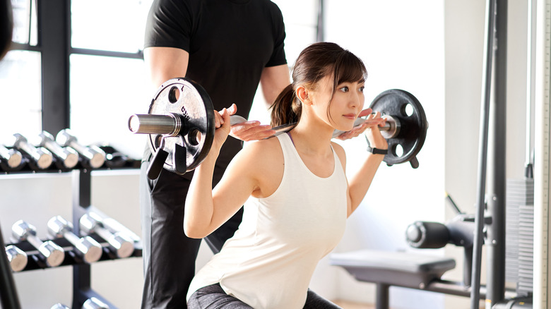 Trainer spotting client at the gym