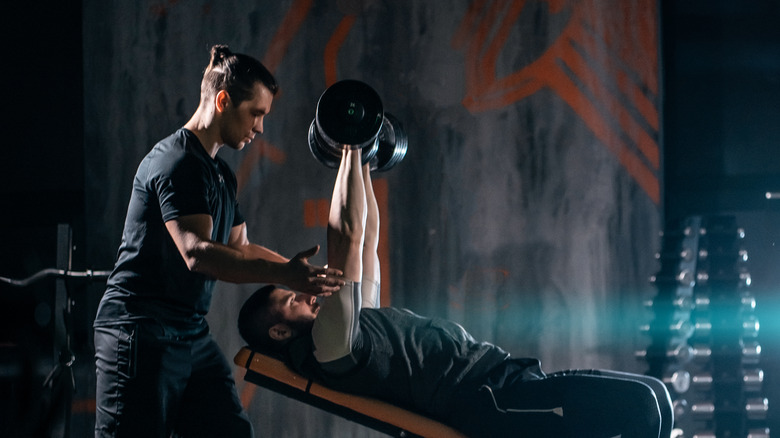 Trainer with client pressing weights