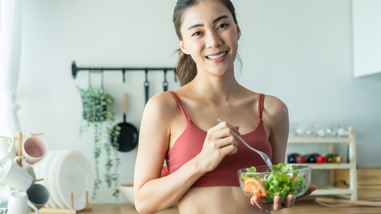 Woman in workout attire eating salad